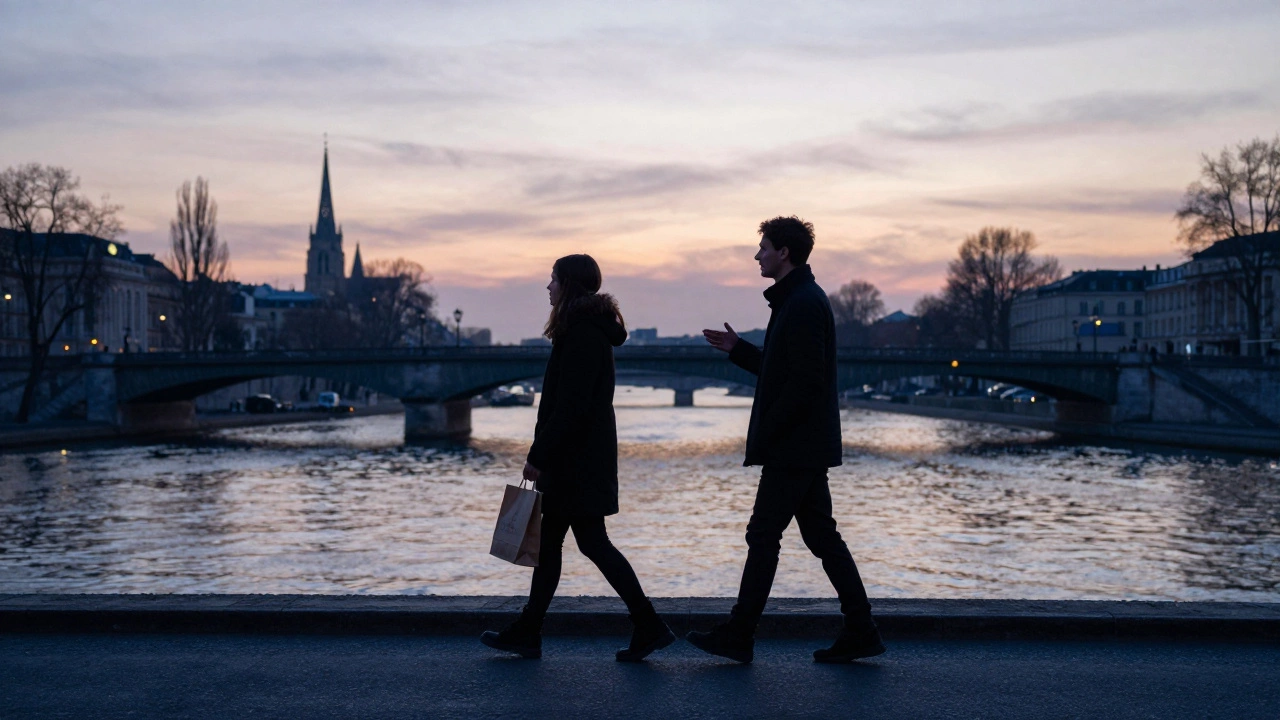 Silhouettes of two figures walking together along the Seine at sunrise, reflections on the water.